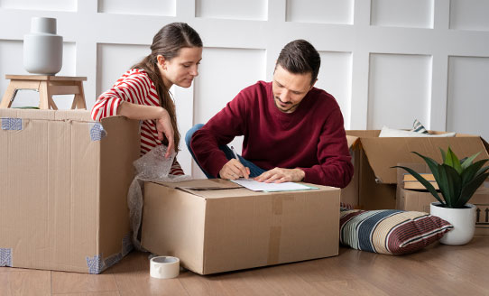 husband and wife mark off printed checklist on top of moving boxes