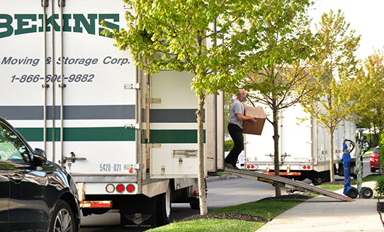 man unloading moving box off of a moving box truck