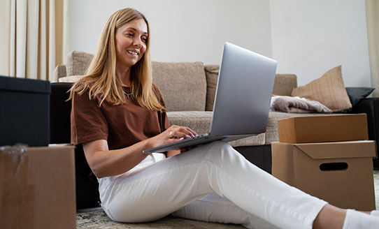 woman on laptop surrounded by moving boxes